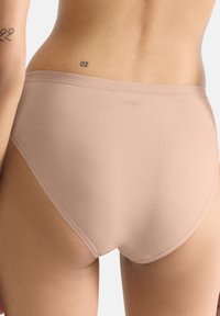 Beigenvärinen Sloggin alushousut, joissa on sileä pinta ja keskisuuri peittävyys, minimalistinen muotoilu ja joustava vyötärönauha.