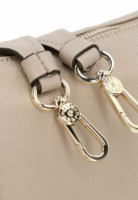 Borsa a tracolla in pelle beige con accessori in metallo dorato, caratterizzata da distintivi tiranti a doppia cerniera e dettagli di cucitura nera sulle cinghie.