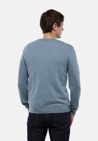 Pull en tricot bleu clair avec de longues manches et un col rond. Présente des poignets et un ourlet côtelés, une texture douce et une coupe décontractée.
