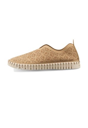Lysebrun slip-on sko med mørke blomster laserudskårne mønstre og en tyk ribbet beige sål på hvid baggrund.
