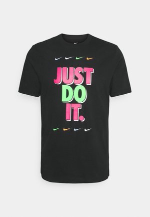 T-shirt en coton noir avec un texte audacieux multicolore « JUST DO IT. » accompagné de différents logos Nike en blanc, vert, orange et noir en dessous.