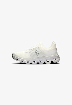 Witte sportieve schoenen met een gestructureerde bovenkant, vetersluiting en een kenmerkende segmentenzool voor flexibiliteit en demping.