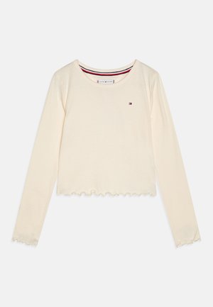 Krema srajca z dolgimi rokavi, izdelana iz mehkega materiala, z zaokroženim izrezom, nabranim robom in majhnim logotipom na sprednji strani.