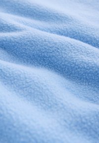 Tissu polaire bleu clair doux avec une surface texturée, légèrement duveteuse et des plis doux.