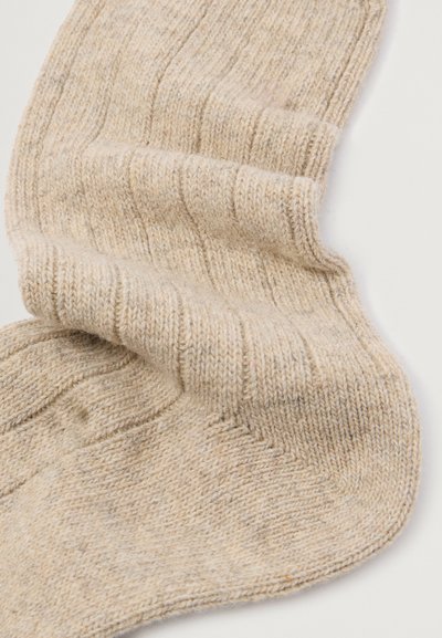 Beige gebreide sokken met een ribbelstructuur, voorzien van een zachte, gestructureerde afwerking en subtiele kleurvariaties.