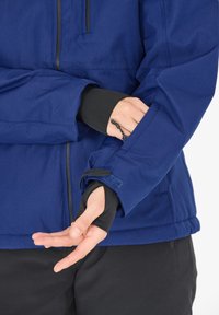 Marine-blau wasserdichte Jacke mit Reißverschluss, verstellbaren Bündchen und schwarzem Innenfutter. Glatte Textur mit unsichtbaren Nahtdetails.