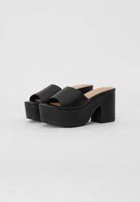 Black platform sandals with an open toe, broad upper strap, and a thick block heel. Smooth leather-like material with a wooden insole.