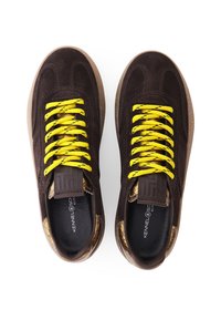 Brown suede sneakers with yellow patterned laces, textured brown rubber outsole, and embossed logo on the tongue.