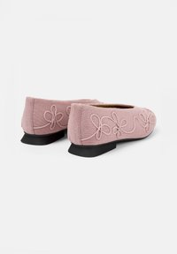 Bailarinas de punto pink con suela de goma negra, que presentan diseños de lazo bordados en los laterales. Punta redondeada y tacón bajo para mayor estabilidad.