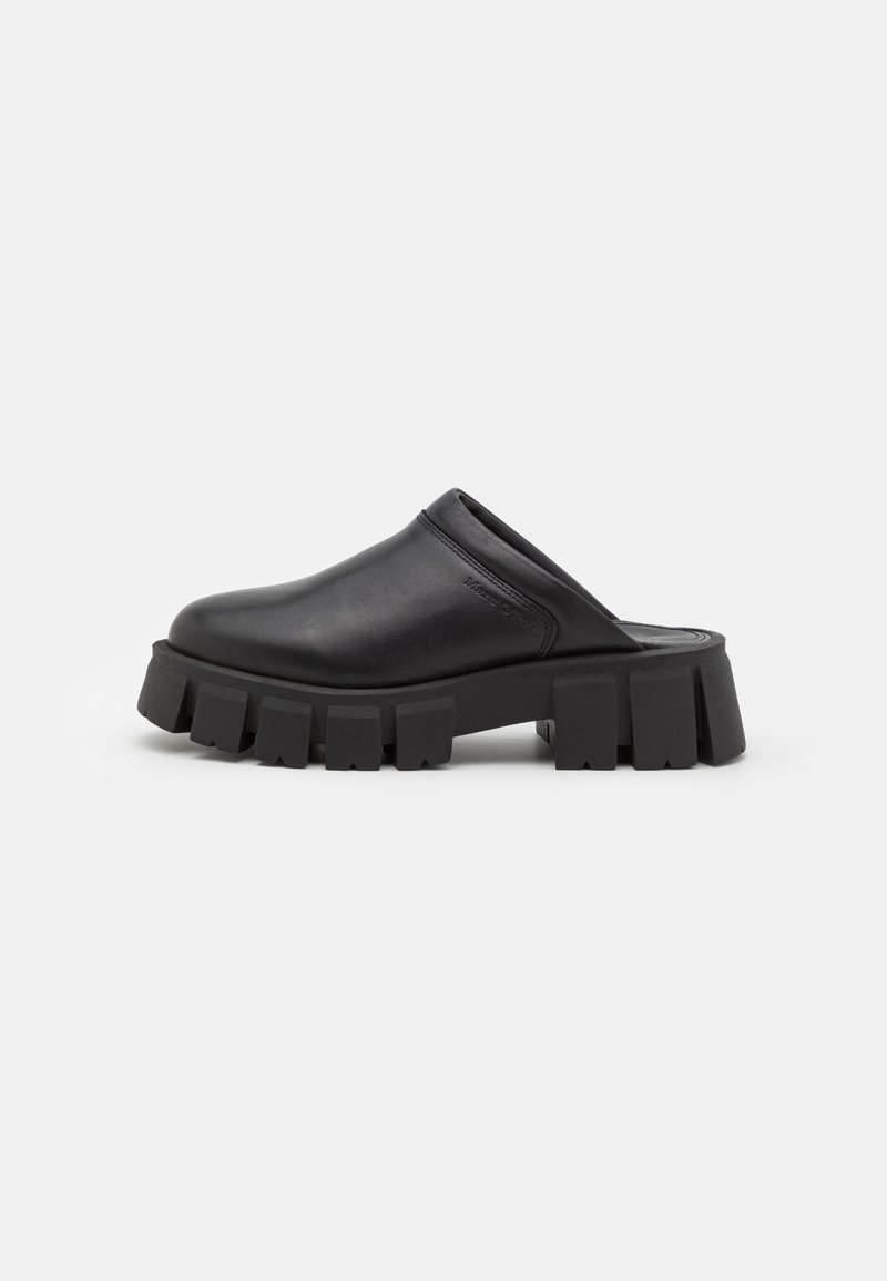 Chaussure noire à enfiler avec bout rond fermé et semelle épaisse et robuste avec une semelle profonde, conçue pour un usage décontracté ou à la mode.