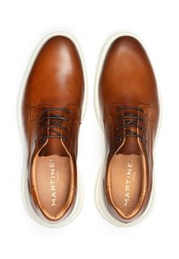 Chaussures en cuir marron au fini lisse, à laçage, avec une semelle blanche contrastante et un branding subtil à l'intérieur. Esthétique minimaliste.