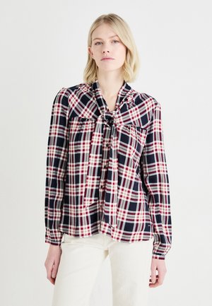 Camicia a scacchi in blu navy, rosso e bianco con dettagli a fiocco al colletto. Maniche lunghe e vestibilità comoda, con chiusura a bottoni davanti.