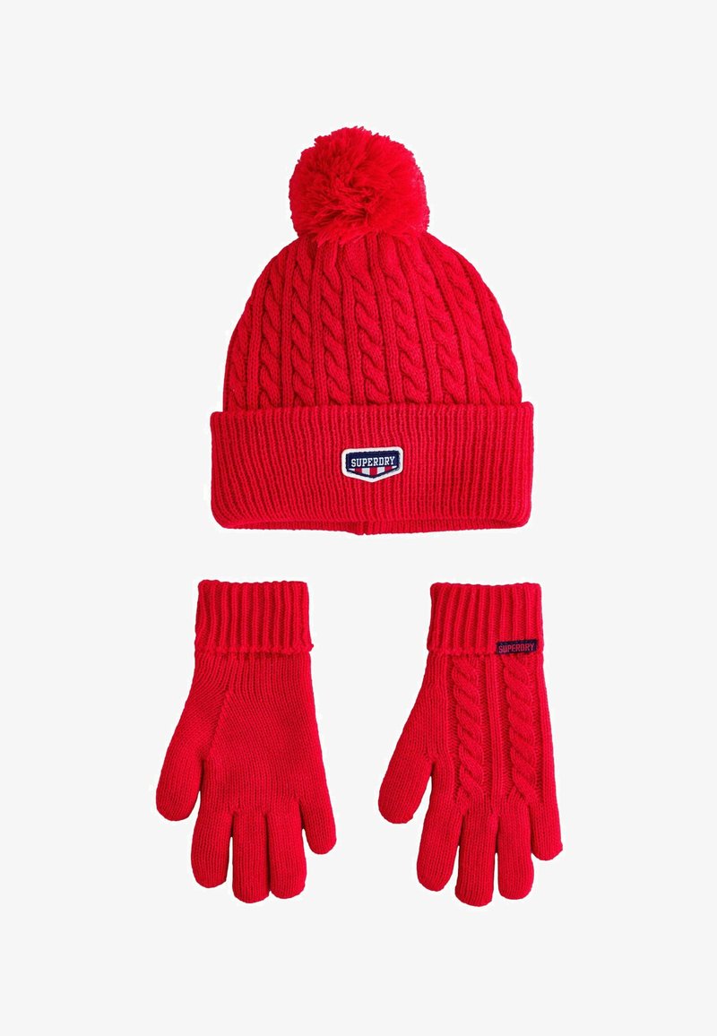 Rode gebreide beanie met een pompon bovenop en een geribde manchet, gecombineerd met bijpassende handschoenen met een geribde textuur en logo-accenten.