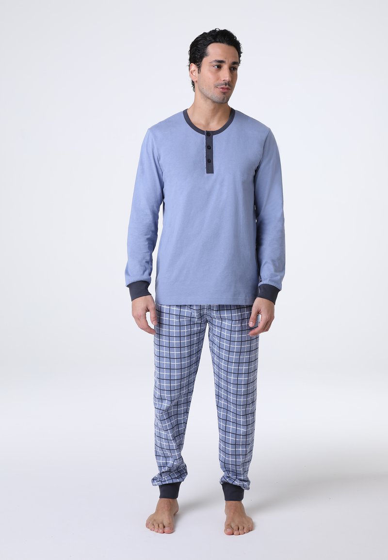 Maglia da pigiama a maniche lunghe azzurra con scollatura grigio scuro e tre bottoni, abbinata a pantaloni da pigiama a quadri blu e bianchi con polsini scuri.