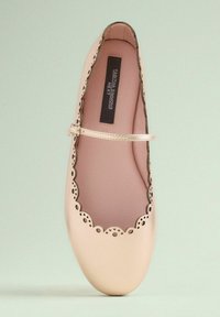 Helle rosa Ballerinas mit gewellten Kanten und durchbrochener Verzierung. Verfügt über einen dünnen metallischen Riemen und eine glatte, abgerundete Zehenpartie.
