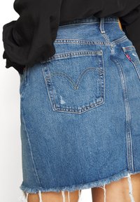 jeanskjol i blekblått med fransade kanter. Har bakfickor med ett hjärtformat sömnadsmönster och en liten m ärkeslapp.