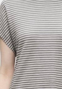 Κορμός με κοντομάνικο πουκάμισο με οριζόντιες γκρι και λευκές ρίγες, ανοιχτός τόνος δέρματος ορατός στο αριστερό χέρι.