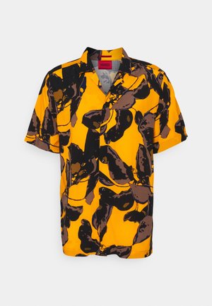 Chemise à manches courtes boutonnée avec un fond jaune vif et de grands motifs abstraits noirs et marron en forme de feuilles, col plié.