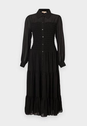 Črna obleka z dolgimi rokavi, ki ima nabrano zgornji del, zapenjanje na gumbe spredaj, večplastno krilo in ovratnik. Izdelana je iz lahkega materiala.