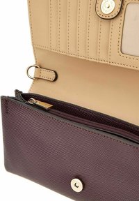 Portefeuille texturé beige et violet foncé avec plusieurs emplacements pour cartes, poche zippée et fermeture à bouton pression, montré ouvert.