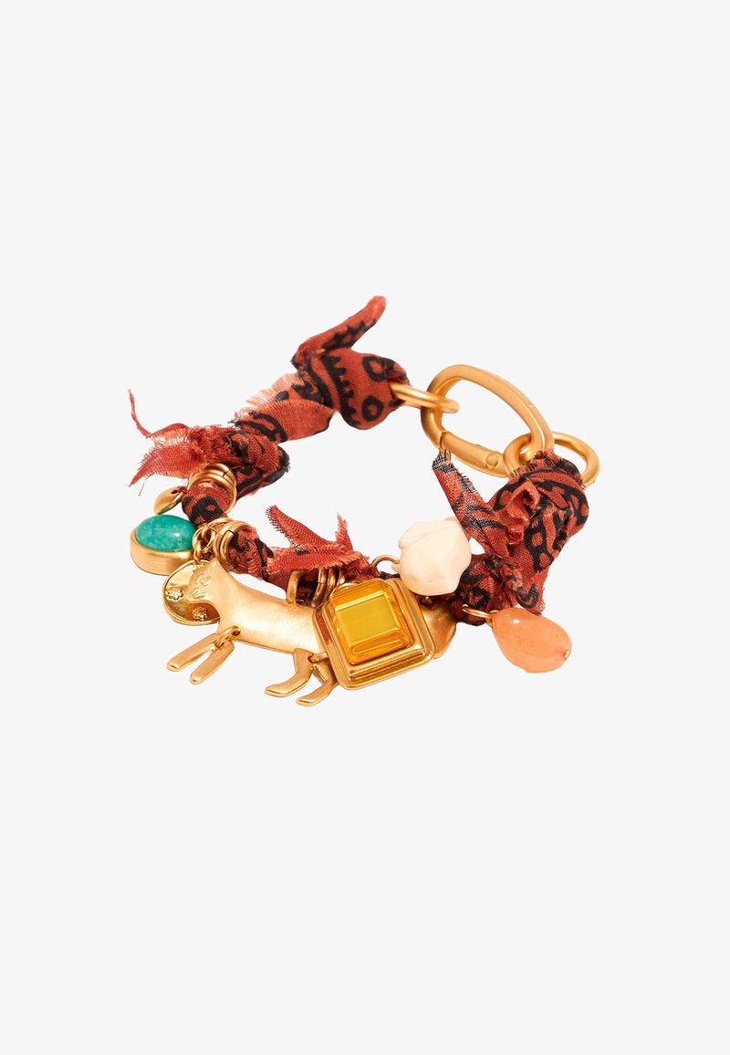 Pulsera de tono dorado con una banda de tela roja estampada, un charm con forma de perro y detalles de piedras preciosas coloridas.