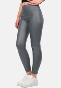 Leggings a vita alta, aderenti, realizzati con un materiale grigio elegante, caratterizzati da una texture liscia e dettagli di cucitura sottili. Abbinati a sneakers bianche.