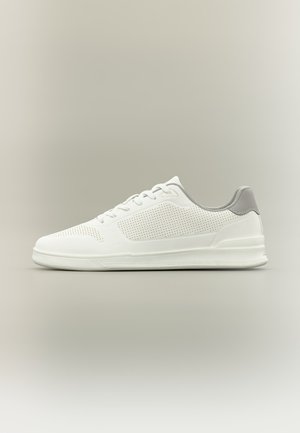 Weißer Sneaker mit niedrigem Schaft, perforierten Details, grauem Fersenlasche, weißer Sohle und weißen Schnürsenkeln auf neutralem Hintergrund.