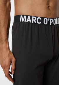 Svarta boxershorts med en mjuk, stretchig midja som har "MARC O'POLO" i vita bokstäver. Slät tygkvalitet och avslappnad passform.