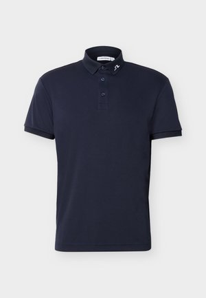 Tricou polo cu mâneci scurte, albastru marin, cu trei nasturi și un mic logo alb pe gulerul stâng, pe un fundal simplu.