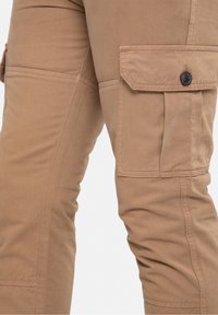 Tan cargobroeken gemaakt van duurzaam stof, met zijzakken, een gladde textuur en knoopdetails op de zakflappen.