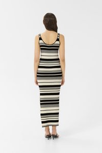 Robe sans manches rayée en crème et noir, design ajusté, longueur genou, avec un dos en V profond et une texture côtelée. Fente en bas.