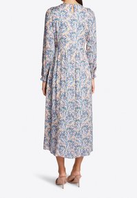 Vestido midi floral en tejido suave, con un diseño en tonos pastel y acentos en azul y amarillo, mangas largas y detalle de abertura en la espalda.