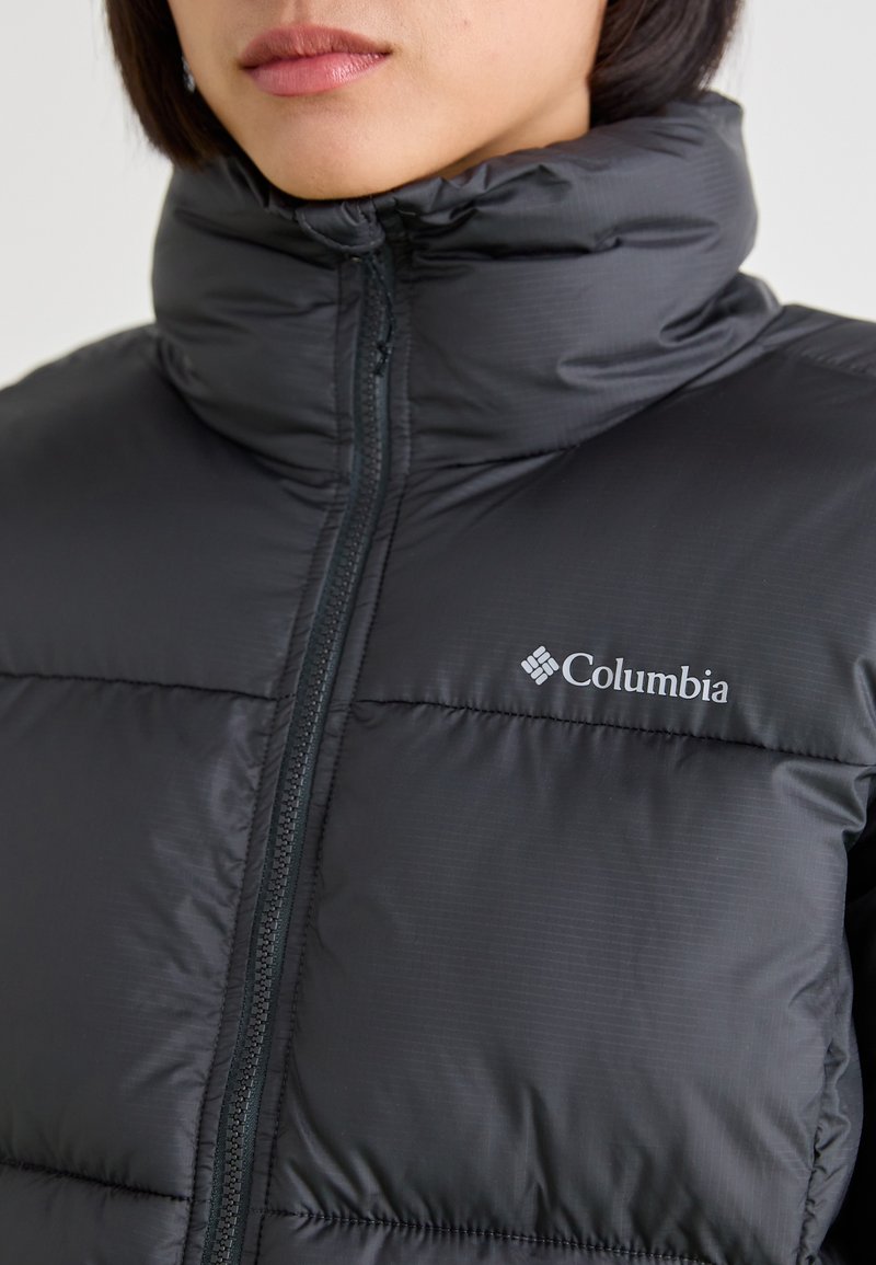 Zwarte gewatteerde jas met een hoge kraag en een rits aan de voorkant. Voorzien van horizontaal gestikte secties en een Columbia-logo aan de linkerkant.