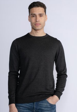 Donkergrijze, lange mouw crewneck trui met geribde manchetten en zoom, gemaakt van zachte stof. G gedragen over aansluitende blauwe spijkerbroek.