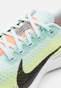 Nike Pegasus Turbo IV trkaća cipela u svijetloplavoj, narančastoj i zelenoj boji. Sadrži teksturiranu mrežicu na gornjem dijelu, podstavljen okovratnik, crni Swoosh logo i bijeli potplat.