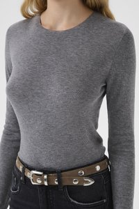Grå langermet genser med rund hals, kombinert med et brunt belte med sølvdetaljer og nagler, brukt over mørke denimjeans.