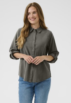 Graues Hemd mit Kragen und hochgekrempelten Ärmeln, aus weichem Stoff, kombiniert mit hellblauen Jeans.