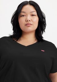 Black V-neck t-shirt made of smooth cotton with a relaxed fit. Features a small red Levi's logo on the left chest area.