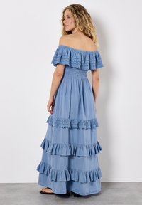 Maxikleid aus hellblauem Stoff, schulterfrei mit geschichteten Rüschen, gerafftem Oberteil, strukturierten Akzenten und einer lässigen Silhouette.