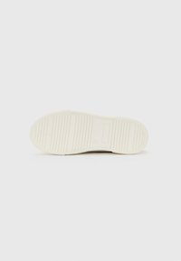 White rubber sole of a shoe with horizontal grooves and size number "33" embossed near the arch area on a plain background.