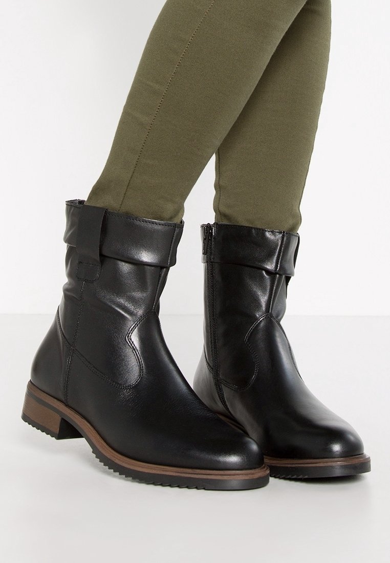 Bottines en cuir noir avec un revers, fermeture éclair latérale et un petit talon empilé. Surface texturée avec une finition lisse et un accent en bois.