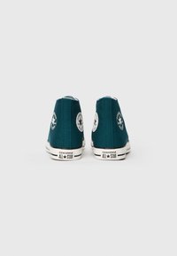 Sneaker alte di tela teal con suole in gomma bianca, caratterizzate da toppe con logo circolare e dettagli neri sul tallone e sulla suola.