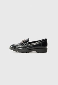 Black leather loafers with a glossy finish, featuring a decorative hardware accent and a thick, textured rubber sole.