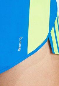 Sportieve shorts met een blauw en neon groen kleurenschema, een gladde textuur, met een ClimaCool-logo aan de zijkant en een contrasterend streepdessin.
