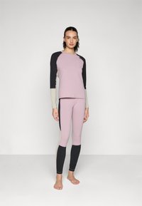 Rosa treningsgenser med svarte og kremfargede ermer, kombinert med rosa tights med svarte sidestriper. Laget av elastisk, glatt stoff.