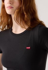 T-shirt nera a maniche corte realizzata in tessuto morbido, con una piccola etichetta rossa del marchio Levi's sul lato sinistro del petto.