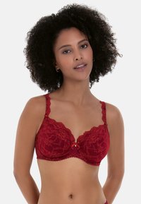 Red lace bra with floral patterns, scalloped edges, and adjustable straps. Features a small bow at the center and a textured design.
