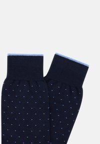 Marina blå strumpor med ljusblå accenter och små prickiga mönster. Tillverkade av mjukt material, med en tät vävning och ribbad mudd.