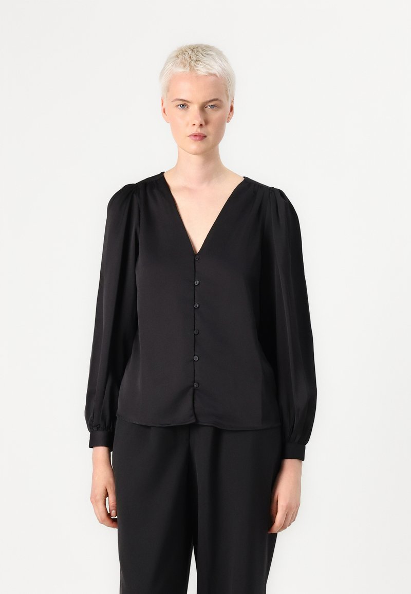 Blusa negra con escote en V, mangas largas abullonadas y botonera en la parte delantera. Textura de tela suave, corte holgado.