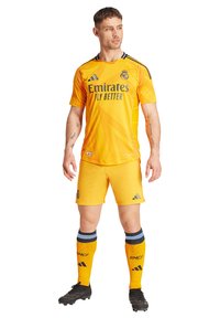 Žuti nogometni dres s kratkim rukavima, s crnim prugama, logom "Emirates" i "RMCF" na čarapama. Uključuje odgovaraju�će kratke hlače i kopačke.